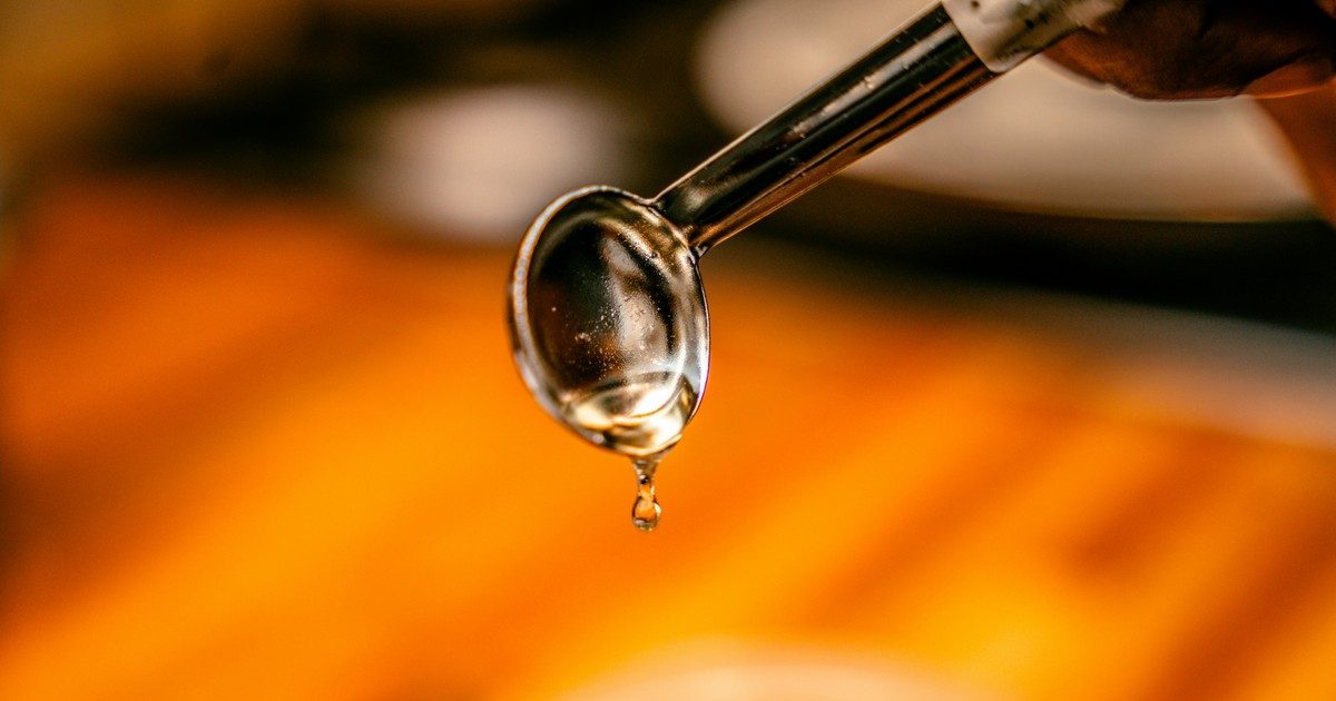 Gota de glicerina transparente cayendo de una cuchara